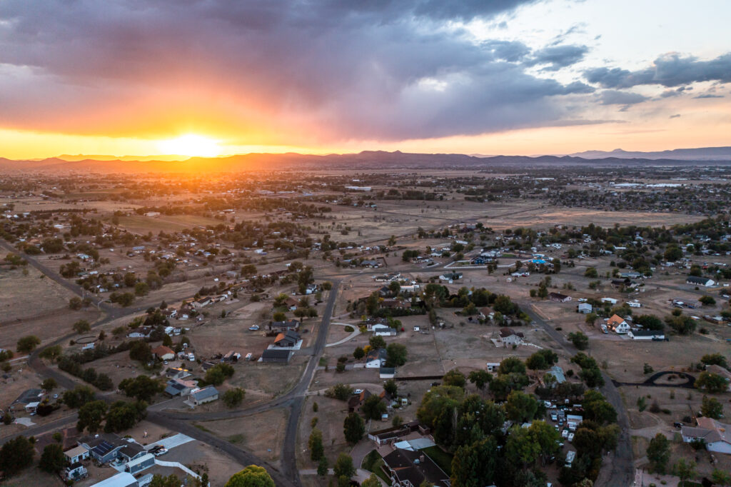 Aerial sunset view of Chino Valley, Arizona showing residential homes, open acreage, and distant mountain ranges