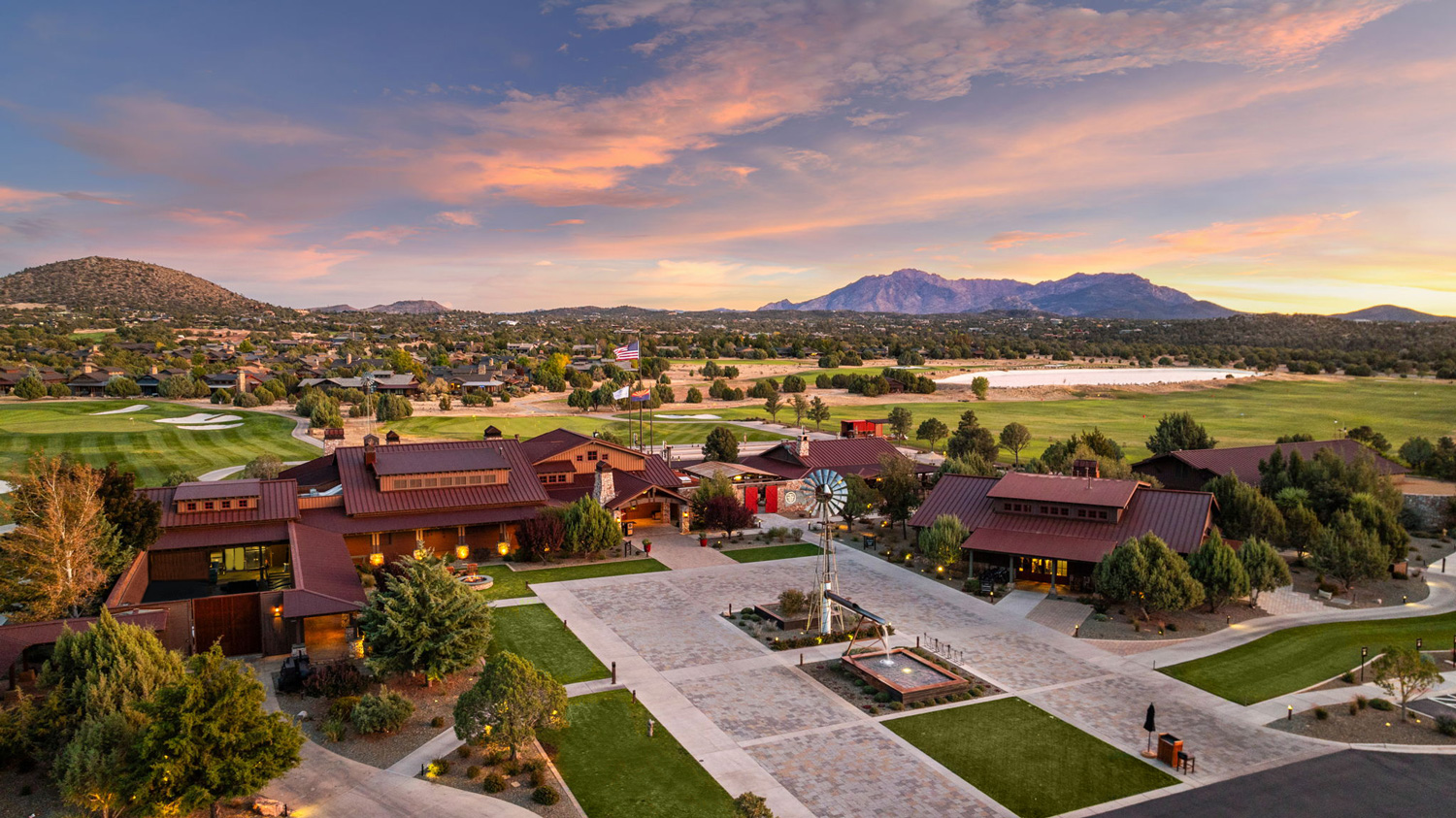 Aerial sunset view of Talking Rock golf club and ranch-style clubhouse with mountains in the distance